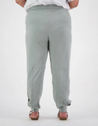 Tapered Track Pants with Hidden Pouch shown from back view in soft sage green color, featuring tapered legs, elastic cuffs, and concealed inner pouch design. Paired with white top to showcase relaxed, comfortable fit and practical medical-wear styling.